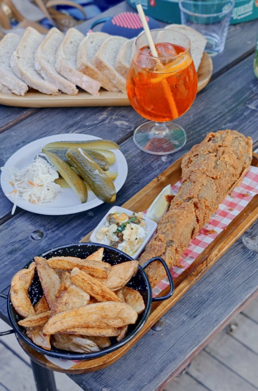 Ropogós hekk rúd Aperollal és savanyúsággal a piknikasztalon
